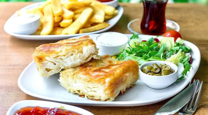 Su böreği with salad, olives, jam, chips and a glass of Turkish tea