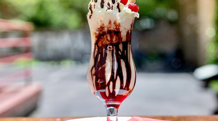 An ice-cream sundae with chocolate, cream and strawberries in the garden